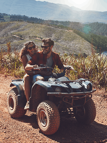 A cheerful couple driving a quad bike through hills