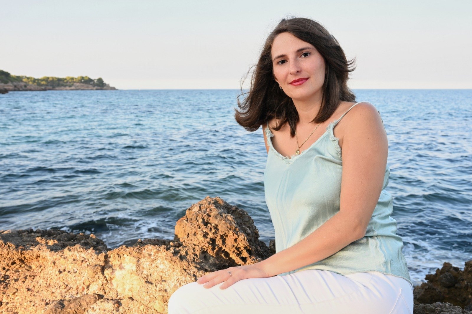 Laura, one of the founders and a guide, sitting on a rock facing the sea