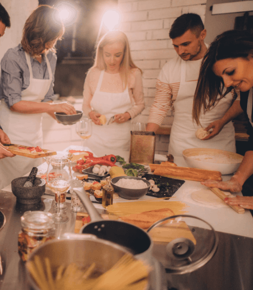 Several people are cooking around a table full of ingredients