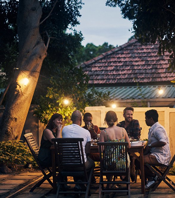 Diners seated at a table, talking and enjoying themselves, in the courtyard of a house